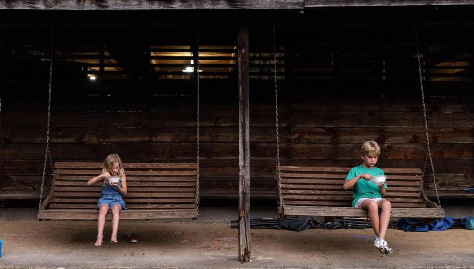 Two children eat ice cream on the porch of a tent at Rock Springs Camp Meeting in Denver, N.C., on Friday, August 10, 2023.