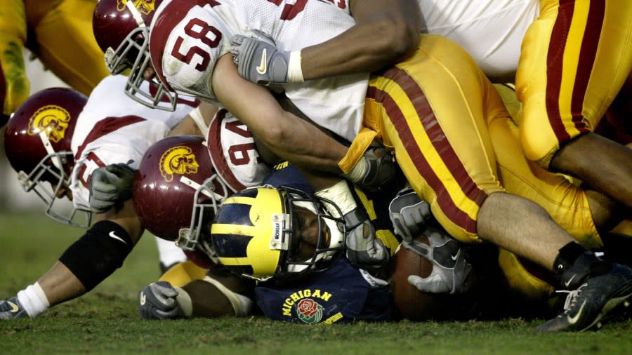 Perry is shown with a grimace on his face while four USC defenders lay on top of him.