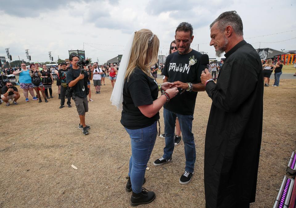 Bridget and Martin Arrieta, of Evansville, get married in front of the Louder Than Life sign on the first day of Louder Than Life on Thursday, September 21, 2021