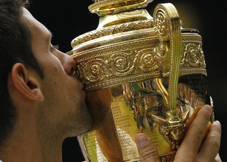 FILE - Serbia's Novak Djokovic kisses the trophy after defeating Spain's Rafael Nadal in the men's singles final at the All England Lawn Tennis Championships at Wimbledon, July 3, 2011. Djokovic will be trying to set the record for the most Grand Slam singles trophies won by a man when he goes for what would be No. 23 against Casper Ruud in the French Open final on Sunday, June 11, 2023. Djokovic enters that match with 22, tied with his rival Rafael Nadal. Roger Federer, who announced his retirement last year, is next with 20. (AP Photo/Kirsty Wigglesworth, File)