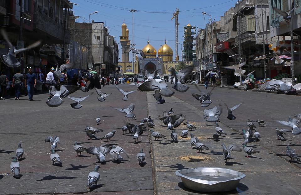 In this Wednesday, May 21, 2019, photo, pigeons fly outside the golden-domed shrine of Imam Moussa al-Kadhim in Kadhimiya district in north Baghdad, Iraq. Many shop owners in the Shiite holy neighborhood of Kadhimiya, have seen their sales drop sharply over the past year since U.S. President Donald began reimposing sanctions on Iran, home to the largest number of Shiite Muslims around the world. (AP Photo/Khalid Mohammed)