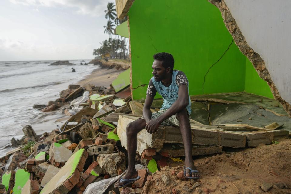 Dilrukshan Kumara looks at the ocean sitting by the wreck of his family house destroyed by erosion in Iranawila, Sri Lanka, Saturday, June 17, 2023. Much like the hundreds of other fishing hamlets that dot the coastline, the village of Iranawila suffers from coastal erosion. (AP Photo/Eranga Jayawardena)