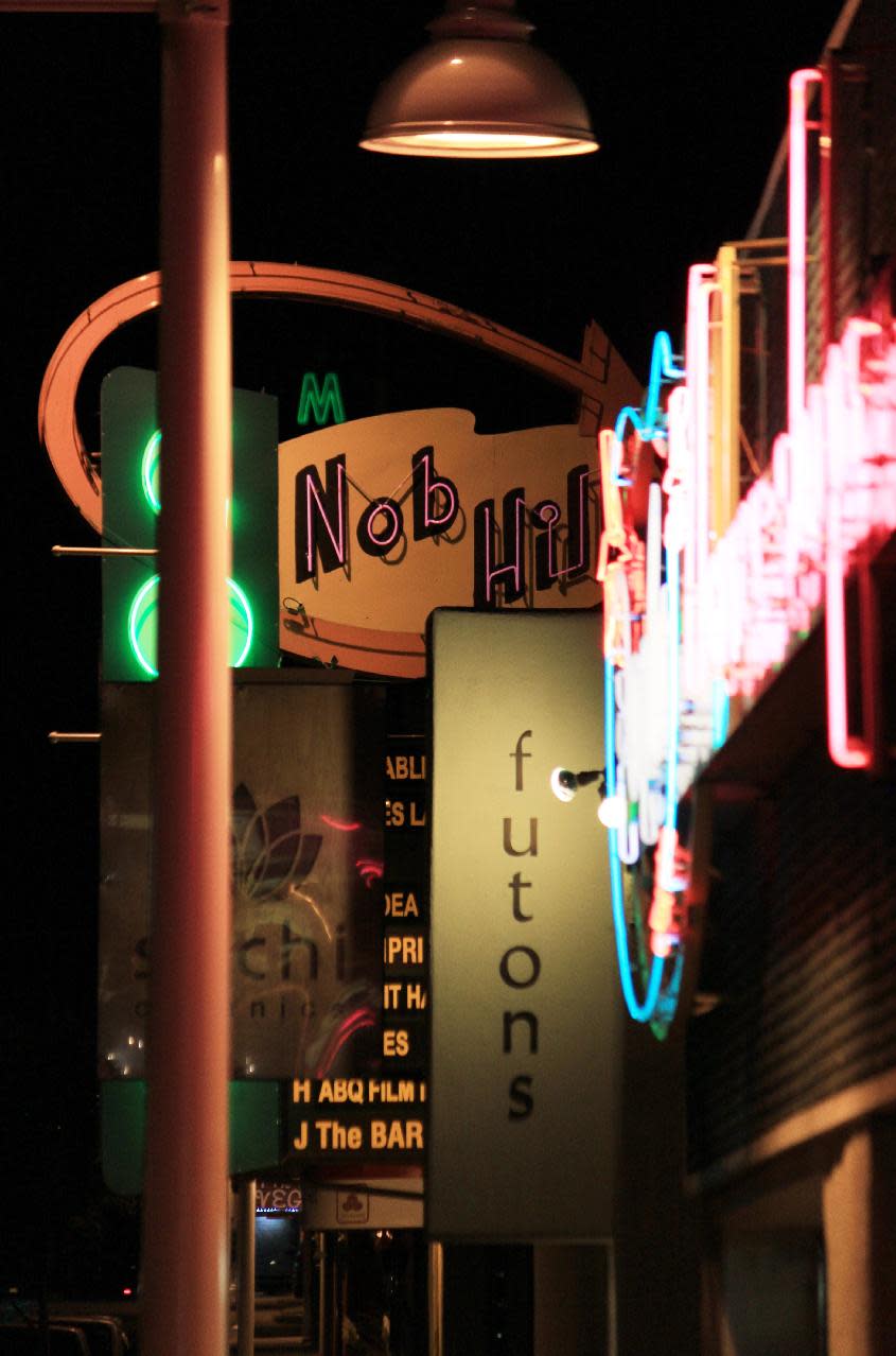 In this Sept. 17, 2013 photo vintage and modern neon signs hangs above the sidewalk in the Nob Hill district along historic Route 66 in Albuquerque. A self-guided tour along this section of the route offers boutiques, restaurants and a parade of neon. (AP Photo/Susan Montoya Bryan)