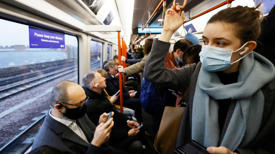 Commuters, many of whom are wearing face coverings, travel on a packed commuter train.