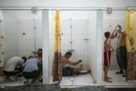 Wrestlers try to recover on the shower room after they competed on the last day of the 660th instalment of the annual Historic Kirkpinar Oil Wrestling championship, in Edirne, northwestern Turkey, Sunday, July 11, 2021.Thousands of Turkish wrestling fans flocked to the country's Greek border province to watch the championship of the sport that dates to the 14th century, after last year's contest was cancelled due to the coronavirus pandemic. The festival, one of the world's oldest wrestling events, was listed as an intangible cultural heritage event by UNESCO in 2010. (AP Photo/Emrah Gurel)