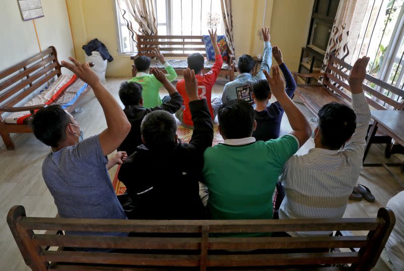 FILE PHOTO: Myanmar nationals including those who said they are police and firemen and recently fled to India flash the three-finger salute at an undisclosed location