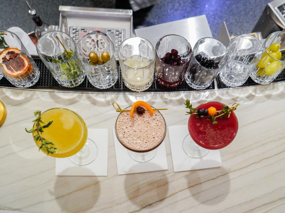 An aerial view of a bar with three cocktails on a white, marble counter