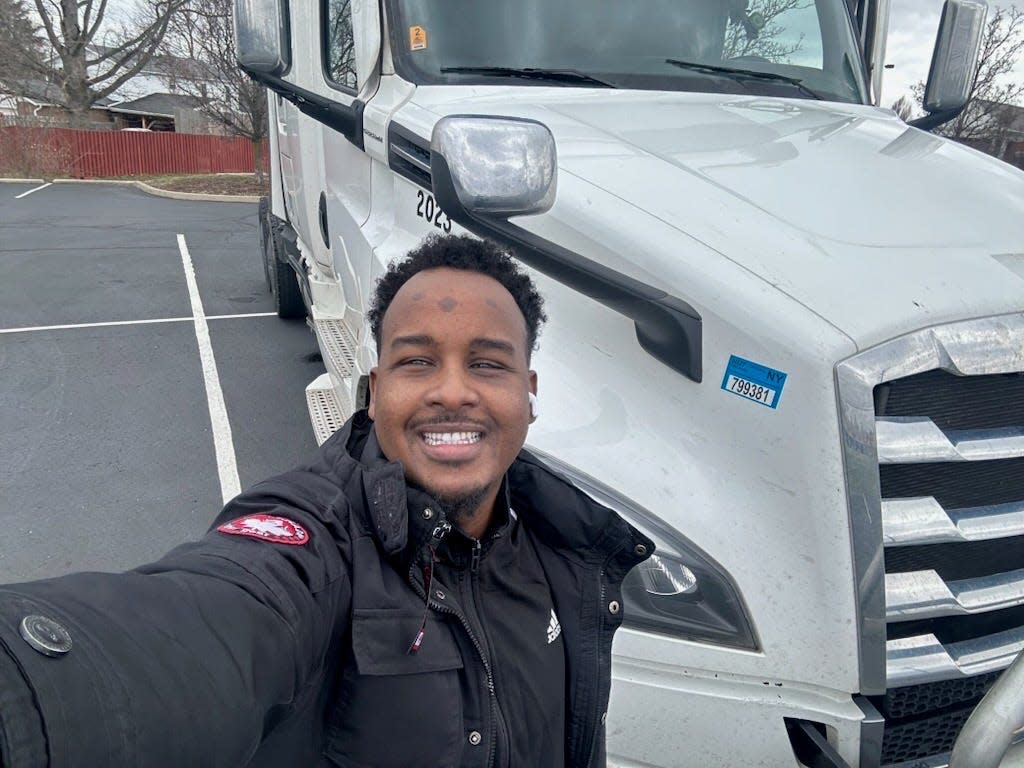 Suud Olat, a former Somali refugee, with the white long-haul truck he drives for work.