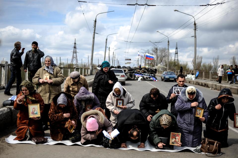Women pray for peace near a regional administration building that was seized by armed pro-Russian activists in the eastern Ukrainian town of Slovyansk, Ukraine, Monday, April 14, 2014. A pro-Russian mob stormed a Ukrainian police station in Horlivka, another city near the Russian border. Later in the day, armed men in masks also seized control of a military airport outside the city of Slovyansk, also in the Donetsk region bordering Russia. (AP Photo/Evgeniy Maloletka)