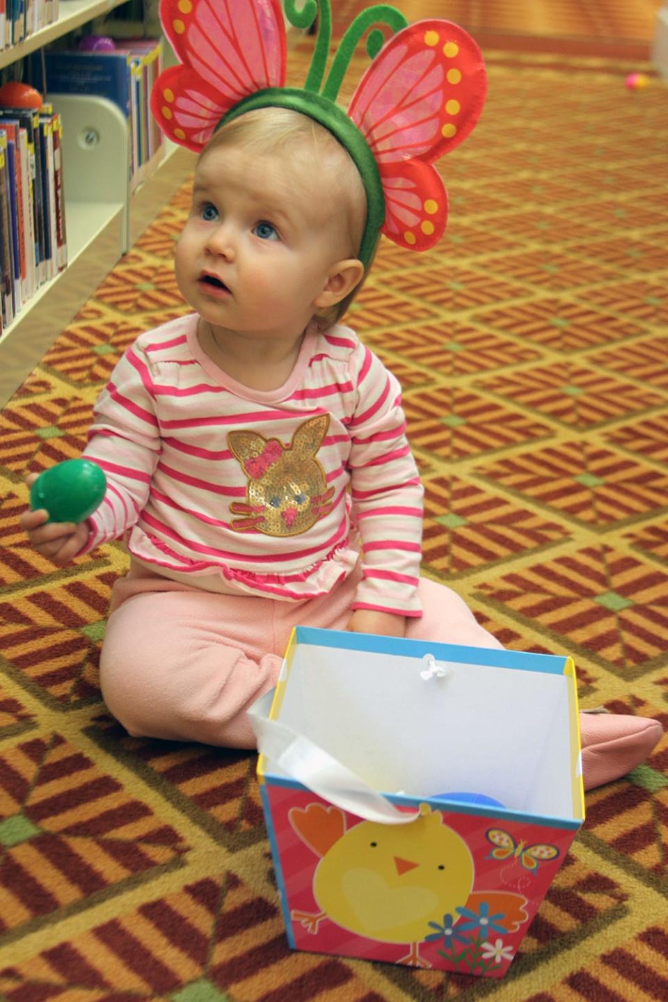 Fiona Douglas, 1, goes through her Easter basket at the Petoskey District Library.
