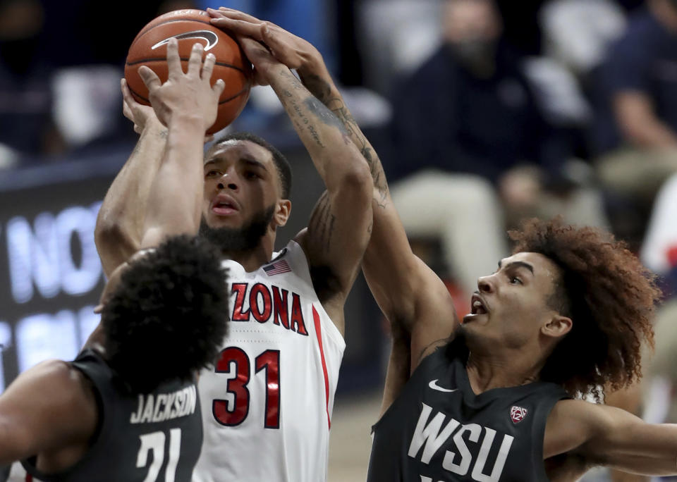 Arizona guard Terrell Brown Jr. (31) gets squeezed into a miss by Washington State center Dishon Jackson (21), left, and guard Isaac Bonton during the first half of an NCAA college basketball game Thursday, Feb. 25, 2021, in Tucson, Ariz. (Kelly Presnell/Arizona Daily Star via AP)