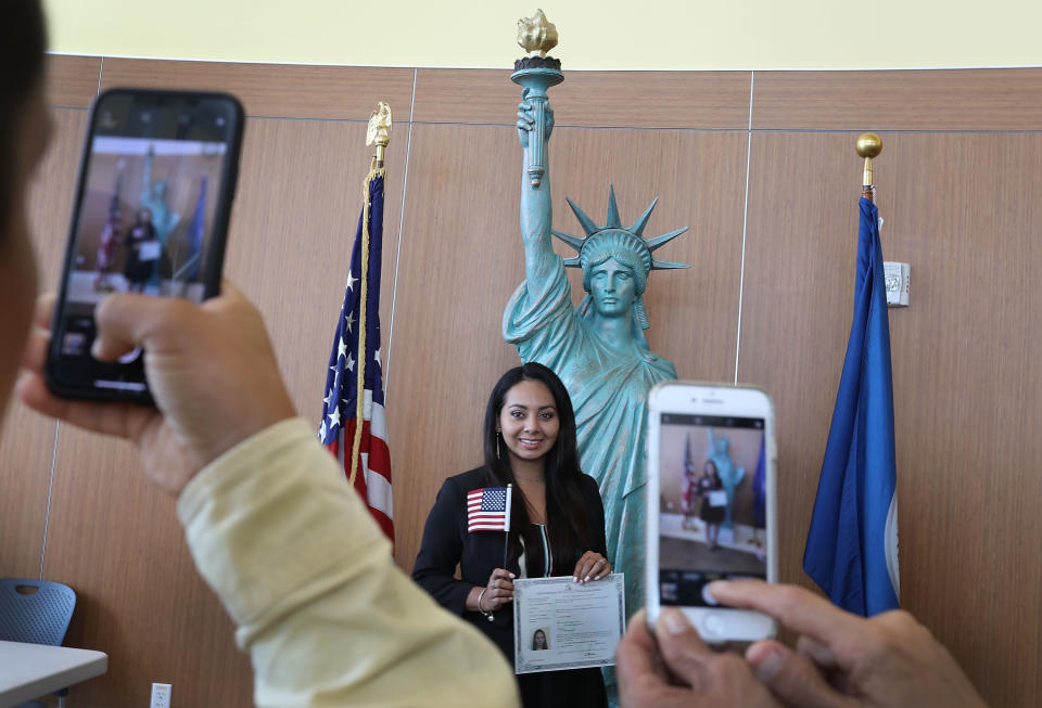 A woman poses in front of a replica of the Statue of Liberty after participating in a USCIS naturalization ceremony on August 17, 2018 in Miami. (Photo by Joe Raedle/Getty Images)