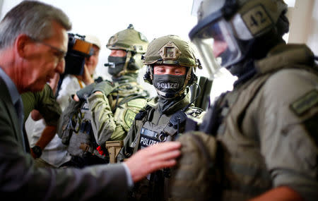 FILE PHOTO: German Interior Minister Thomas de Maiziere speaks with members of the GSG 9 unit of Bundespolizei, Germany's federal police, during the opening of a new headquarters for special forces and anti-terror units in Berlin, Germany August 8, 2017. REUTERS/Hannibal Hanschke/File Photo