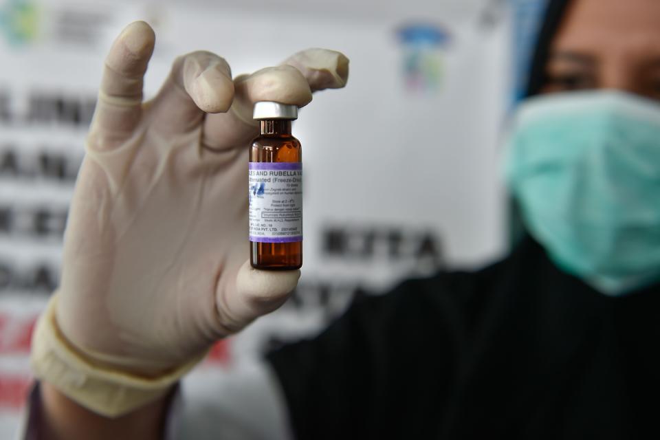 In this file photo a medical worker holds a measles-rubella (MR) vaccine.