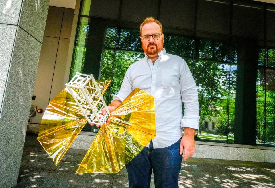 Marco Cross, chief engineer with Brown University's SBUDNIC project, holds a model of the space satellite that will take photos of Earth and record temperature data.