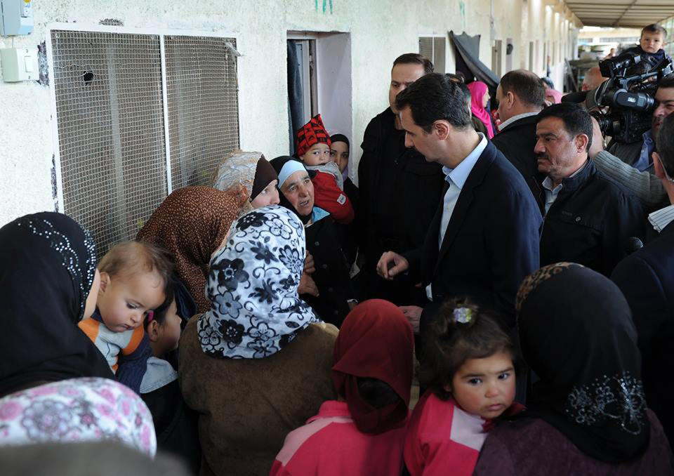 In this photo released on the official Facebook page of Syrian Presidency, Syrian president Bashar Assad, center right, visits a shelter of internally displaced people in the Damascus suburb of Adra, Syria, Wednesday, March 12, 2014. Syria's state TV is reporting that President Bashar Assad has made a rare public appearance, visiting people displaced by the war in the suburb. Syrian troops have been on the offensive in Adra, just northeast of Damascus, after rebels captured parts of it in December, which displaced thousands from the area. A July U.N. estimate said 6.5 million have been uprooted from their homes and displaced within Syria. (AP Photo)