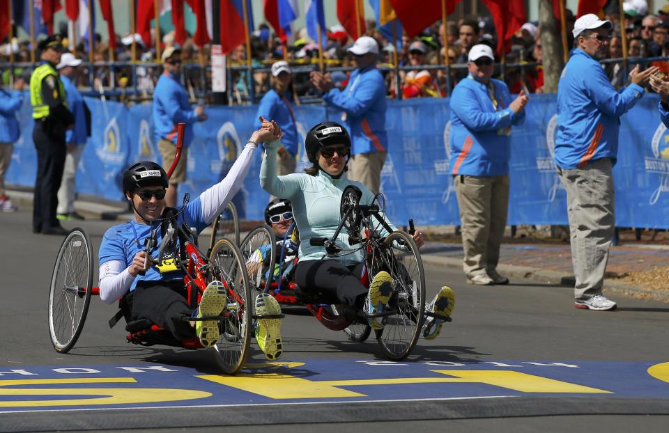 Boston Marathon bombing survivors Patrick Downes (L) and Jessica Kensky cross the finish line at the 118th running of the Boston Marathon in Boston, Massachusetts April 21, 2014. (REUTERS/Brian Snyder)