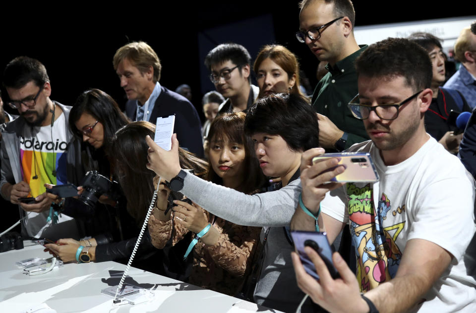 Visitors take pictures of new devices of China's smartphone manufacturer Huawei during an event in Munich, Germany, Thursday, Sept. 19, 2019. (AP Photo/Matthias Schrader)