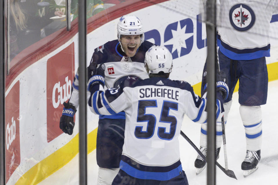 Winnipeg Jets center Dominic Toninato, left, celebrates after scoring a goal with center Mark Scheifele (55) during the third period of an NHL hockey game against the Minnesota Wild, Sunday, Dec. 31, 2023, in St. Paul, Minn. (AP Photo/Bailey Hillesheim)