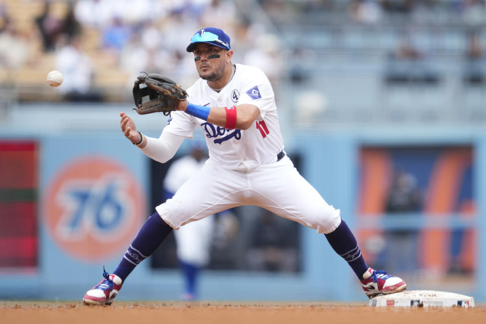 Los Angeles Dodgers second baseman Miguel Rojas (11) catches a throw to second to out Colorado Rockies' Ryan McMahon during the sixth inning of a baseball game in Los Angeles, Sunday, June 2, 2024. Colorado Rockies' Brendan Rodgers grounded in to a double play. (AP Photo/Ashley Landis)