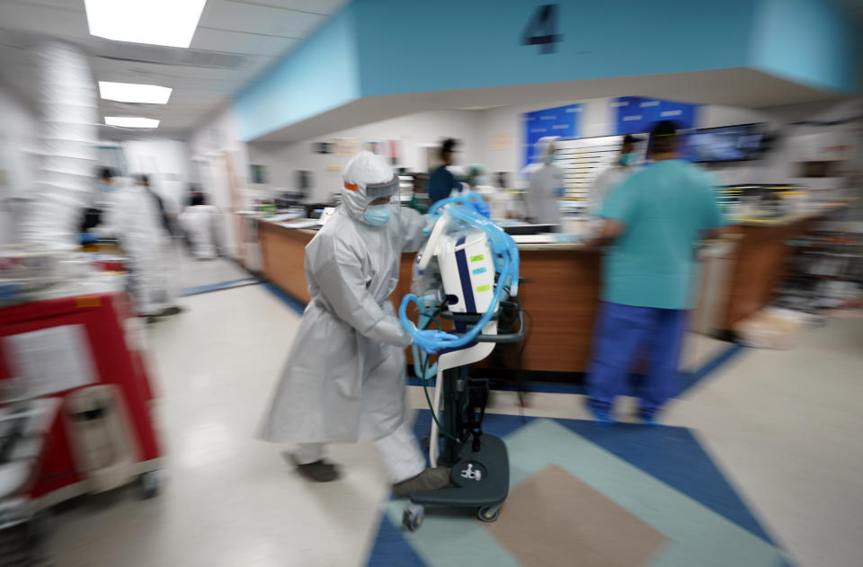 Medical equipment is rushed to a room as medical personnel try to save the life of a patient inside the Coronavirus Unit at United Memorial Medical Center, Monday, July 6, 2020, in Houston. Despite their efforts, the patient died. (AP Photo/David J. Phillip)