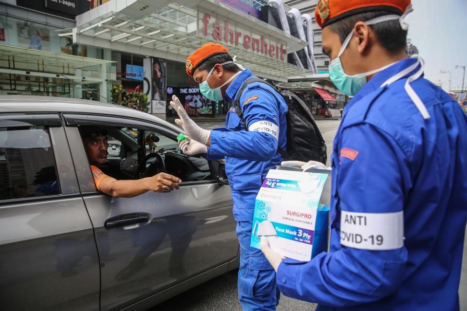 Malaysia Civil Defence Force personnel distribute protective face masks to the public in Kuala Lumpur March 21, 2020. — Picture by Yusof Mat Isa