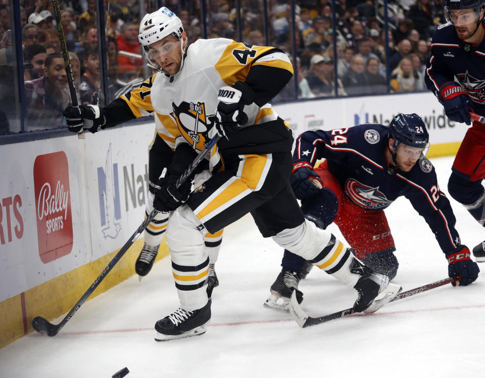 Pittsburgh Penguins defenseman Jan Rutta, left, reaches for the puck in front of Columbus Blue Jackets forward Mathieu Olivier during the second period of an NHL hockey game in Columbus, Ohio, Saturday, Oct. 22, 2022. (AP Photo/Paul Vernon)