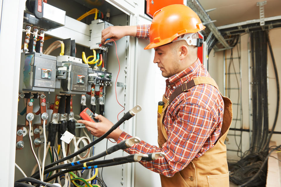 young adult electrician builder engineer worker in front of fuse switch board