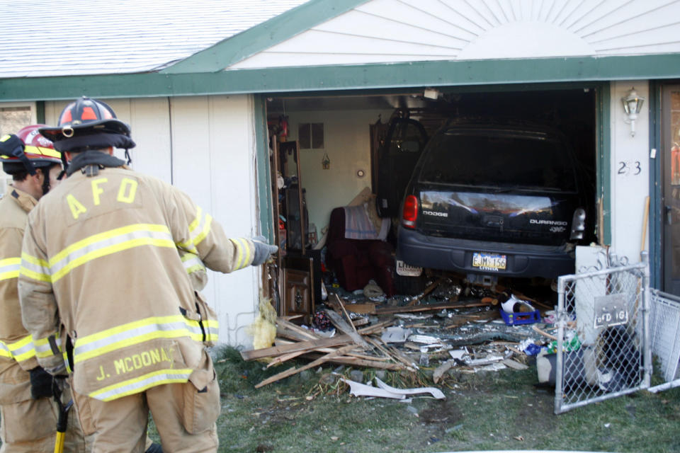 Firemen look over a vehicle that drove completely into a home in Anchorage, Alaska, on Tuesday, Oct. 11, 2011, barely missing the homeowner, who was sitting in a chair that the SUV missed by inches. The driver was taken to the hospital with minor injuries; the homeowner was skaken up but unhurt. (AP Photo/Mark Thiessen)