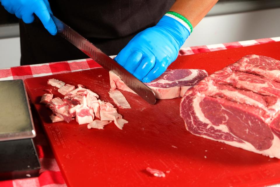 Texas Roadhouse employee and National Meat Cutting Challenge finalist Silvano Vicente trims fat from steaks on Feb. 7.