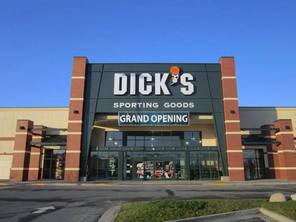 The exterior of a Dick's Sporting Goods location, as viewed from the parking lot. A grand opening banner hangs below the company's logo.