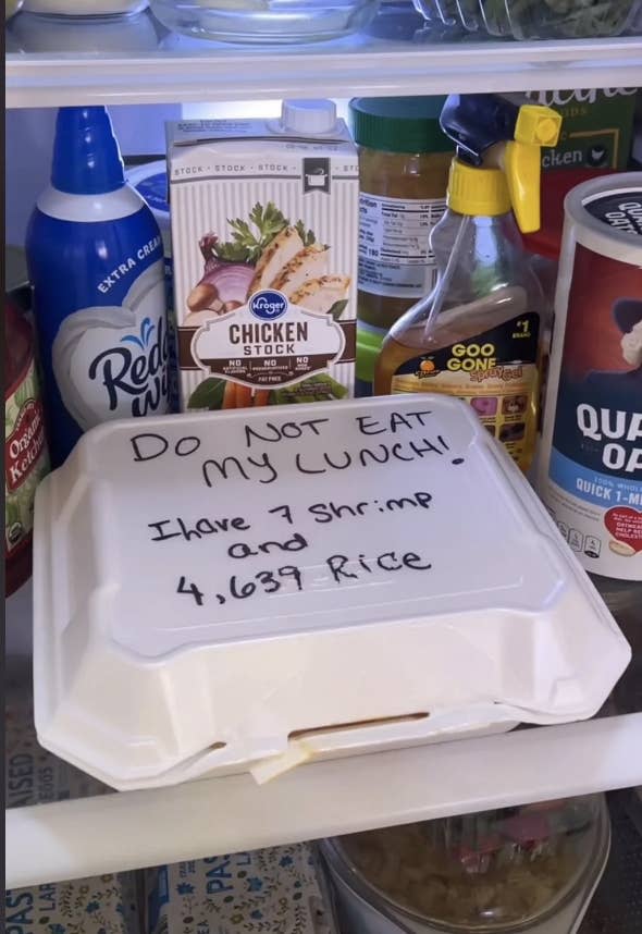 A refrigerator shelf with a labeled takeout container that reads, 