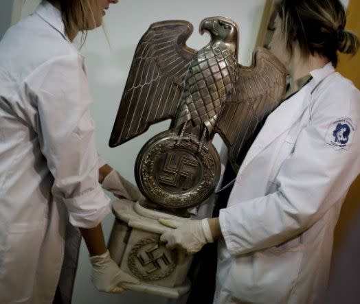 Members of the federal police carry a Nazi statue at the Interpol headquarters. Source: AP Photo/Natacha Pisarenko