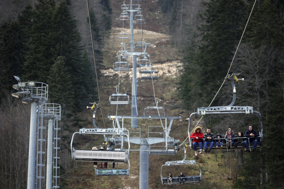 FILE - People ride the chair lift above the ski track without any snow on Bjelasnica mountain near Sarajevo, Bosnia, Wednesday, Jan. 4, 2023. (AP Photo/Armin Durgut, File)