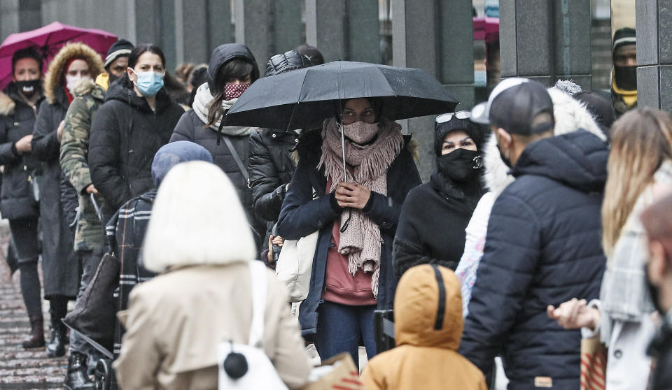 People queue in front of a shop in the city center of Essen, Germany, Monday, Dec. 14, 2020. Germany goes into a nationwide lockdown on Wednesday, Dec. 16, 2020 to fight the COVID-19 pandemic. (AP Photo/Martin Meissner)
