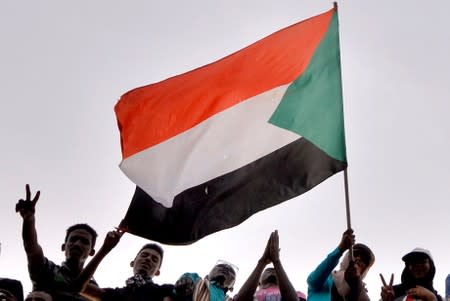 FILE PHOTO: Sudanese demonstrators wave the national flag as they attend a protest rally demanding Sudanese President Omar Al-Bashir to step down, outside the Defense Ministry in Khartoum