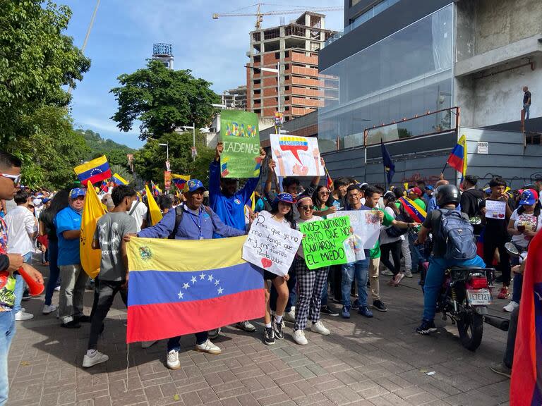 Jóvenes alzan carteles con llamados al fin del gobierno de Nicolás Maduro