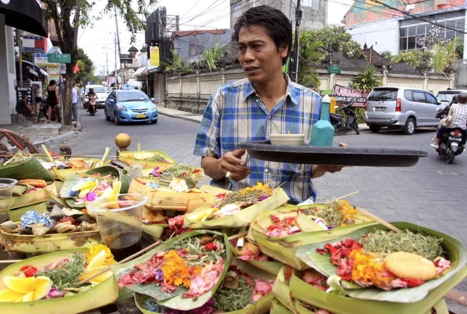 This Aug. 25, 2012 photo shows a Balinese man offering food to local god in Kuta, Bali, Indonesia. It can be hard to find Bali's serenity and beauty amid the villas with infinity pools and ads for Italian restaurants. But the rapidly developing island's simple pleasures still exist, in deserted beaches, simple meals of fried rice and coconut juice, and scenes of rural life. (AP Photo/Firdia Lisnawati)