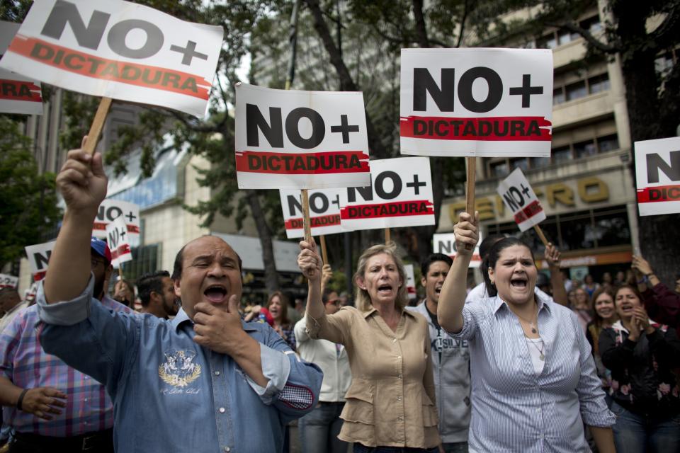 People holding signs with a message that reads in Spanish: "No more dictatorship" take part in a walkout against President Nicolas Maduro, in Caracas, Venezuela, Wednesday, Jan. 30, 2019. Doctors in scrubs, businessmen in suits and construction workers in jeans gathered on the streets of Venezuela's capital Wednesday, demanding Maduro step down from power in a walkout organized by the nation's reinvigorated opposition to ratchet up pressure on the embattled president. (AP Photo/Ariana Cubillos)