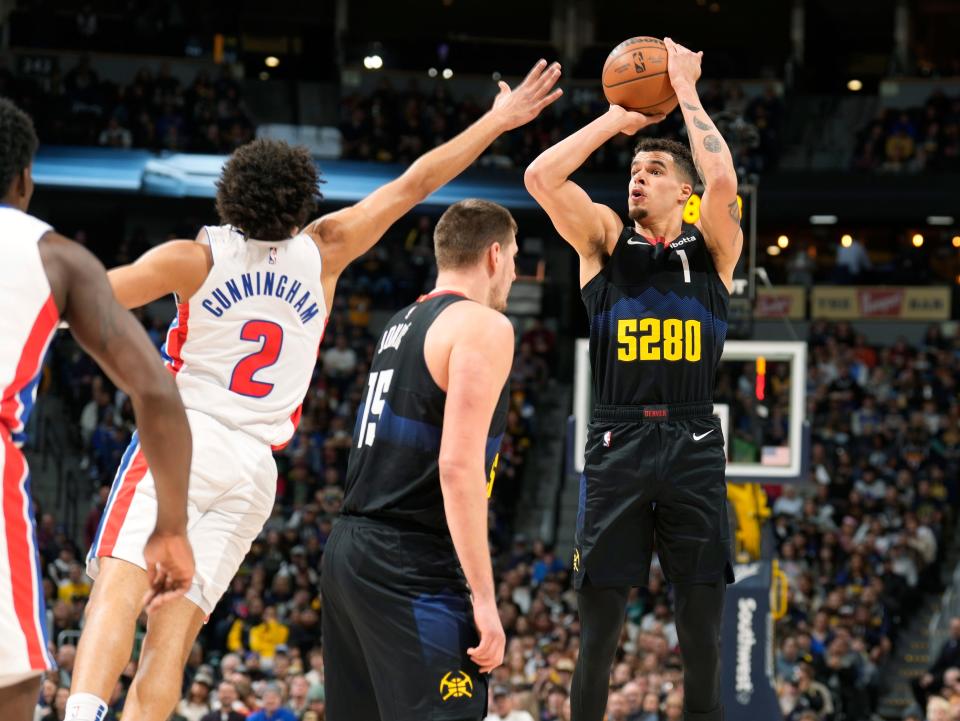 Detroit Pistons guard Cade Cunningham (2) reaches over a pick set by Denver Nuggets center Nikola Jokic (15) to foul forward Michael Porter Jr., right, who takes a 3-point shot in the first half at Ball Arena in Denver on Sunday, Jan. 7, 2024.