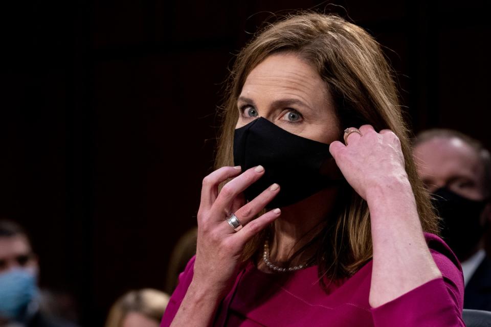 Supreme Court nominee Judge Amy Coney Barrett removes her mask during the Senate Judiciary Committee confirmation hearing