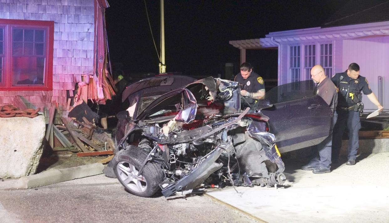 Falmouth police examine a car that was heavily damaged when it crashed into the Patriot Party Boats building at 227 Clinton Ave. Two people were injured and one of them was taken to the hospital by medical rescue helicopter.