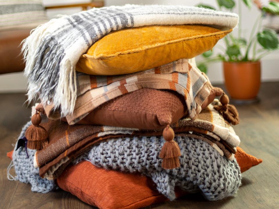 Stack of yellow, terracotta, and brown colored pillows placed on the floor.