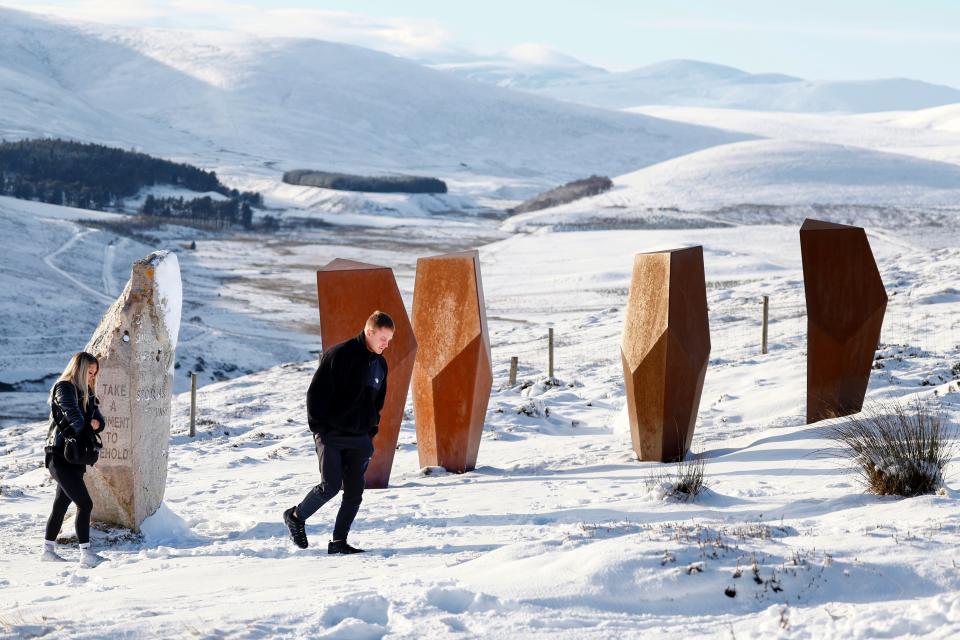 A couple walk past The Watchers Art Installation and A Moment in Time at Corgarff, Scotland (Getty Images)