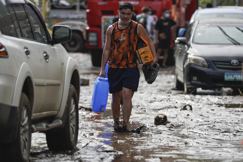 A resident walks along a mud-covered road after floodwaters caused by Typhoon Goni rose inside their village in Batangas city, Batangas province, south of Manila, Philippines on Monday, Nov. 2, 2020. Super typhoon Goni left wide destruction as it slammed into the eastern Philippines with ferocious winds early Sunday and about a million people have been evacuated in its projected path. (AP Photo/Aaron Favila)