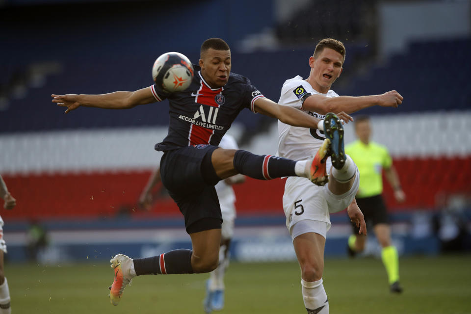 Kylian Mbappe, del PSG, izquierda, disputa un balón con Sven Botman, de Lille, en un partido de la liga francesa en el estadio Parc des Princes, París, Francia, sábado 3 de abril de 2021. Lille ganó 1-0 y quedó como único puntero. (AP Foto/Christophe Ena)