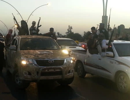 Fighters of the Islamic State of Iraq and the Levant (ISIL) celebrate while sitting on vehicles in the city of Mosul, June 23, 2014. REUTERS/Stringer