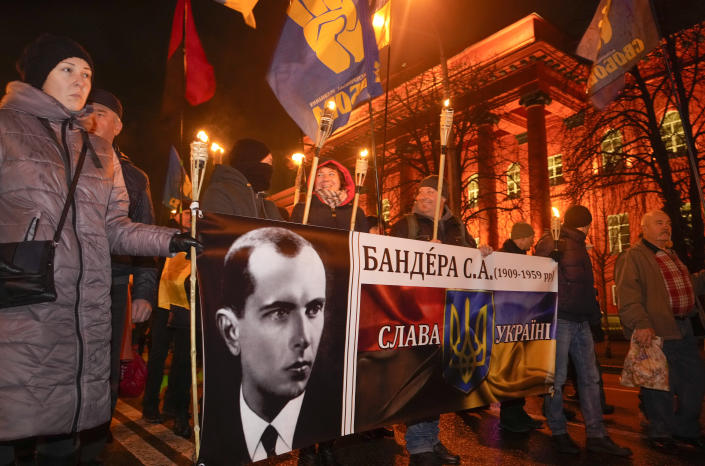 Activists of various nationalist parties carry torches and a portrait of Stepan Bandera during a rally in Kyiv, Ukraine, Saturday, Jan. 1, 2022. The rally was organized to mark the birth anniversary of Stepan Bandera, founder of a rebel army that fought against the Soviet regime and who was assassinated in Germany in 1959. (AP Photo/Efrem Lukatsky)
