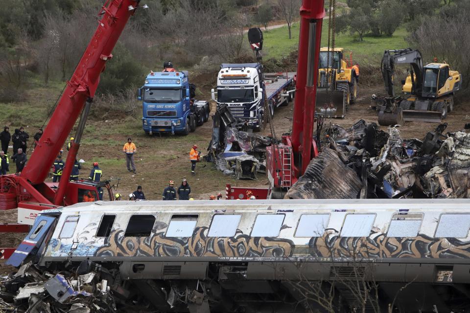 Two cranes try to remove debris from the rail lines after a collision in Tempe, about 376 kilometres (235 miles) north of Athens, near Larissa city, Greece, Thursday, March 2, 2023. Emergency workers are searching for survivors and bodies after a passenger train and a freight train crashed head-on in Tempe, central Greece just before midnight Tuesday. It was the country's deadliest rail crash on record. (AP Photo/Vaggelis Kousioras)