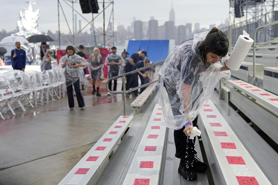 A crew member drys seats with paper towels prior to the start of the Tommy Hilfiger Fall 2022 fashion show at the Skyline Drive-In on Sunday, Sept. 11, 2022, in New York. (Photo by Charles Sykes/Invision/AP)